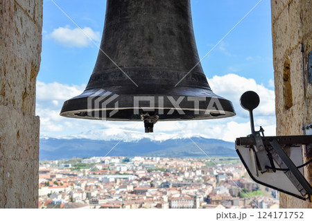 Front view bell atop Cathedral with village in background snow capped mountains 124171752