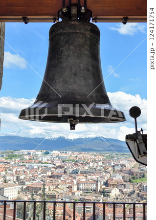 Front view bell atop Cathedral with village in background snow capped mountains 124171754