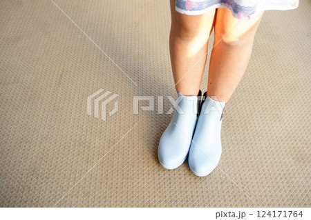 ショート丈のキッズ用レインブーツ。小学5年生の女の子が水色のレインブーツを履いている足元。 124171764