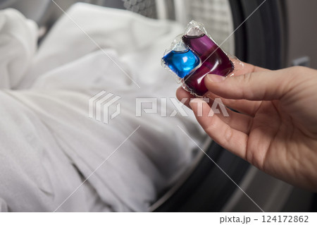 Using Laundry Detergent Pods While Doing Laundry in the Washing Machine with Clothes 124172862
