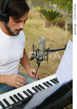 Singer Author Sets Up The Microphone And Sings Playing The Keyboard Singer Author Sets Up The Microphone And Sings Playing The Keyboard 124173454