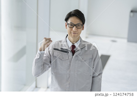 カメラ目線でガッツポーズをする作業服姿の40代の男性　 124174758