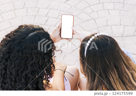 Hands of two girls pointing at cell phone screen, Two girls sitting pointing at blank cell phone screen with space for text Hands of two girls pointing at cell phone screen, Two girls sitting pointing at blank cell phone screen with space for text 124175599