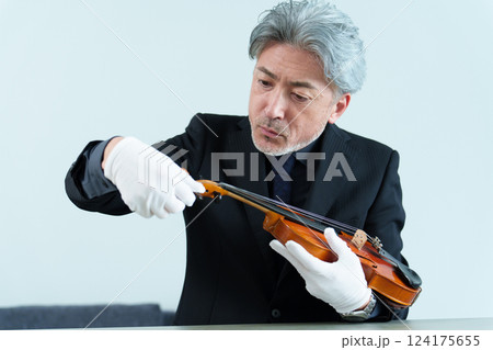 ヴァイオリンを点検する男性 124175655