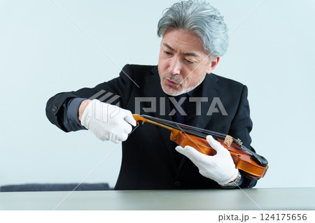 ヴァイオリンを点検する男性 124175656