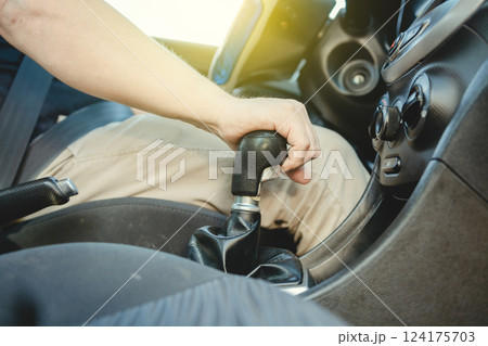 Close-up of driver hand on the gear lever of a car, Driver hand grabbing car gear stick, closeup of hands accelerating on gear stick Close-up of driver hand on the gear lever of a car, Driver hand grabbing car gear stick, closeup of hands accelerating on gear stick 124175703