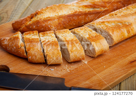 Cut fresh french baked baguettes on wooden desk Cut fresh french baked baguettes on wooden desk 124177270