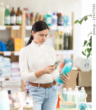 Woman scanning the barcode of shampoo and shower gel packaging 124177282