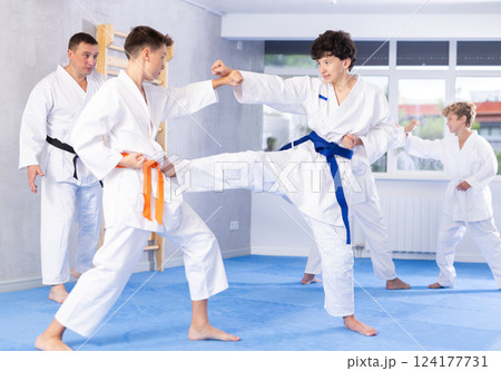 Diligent preteen attendee of karate classes fighting with his opponent in sports hall 124177731