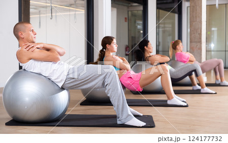 Group of people doing crunches on swiss balls 124177732