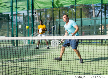 Concentrated man padel player hitting ball with racket 124177787