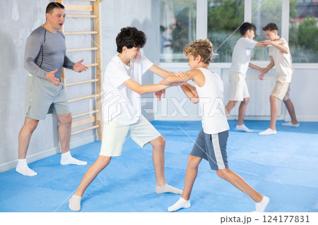 Teenage boys sparring in training room during self-defence workout 124177831