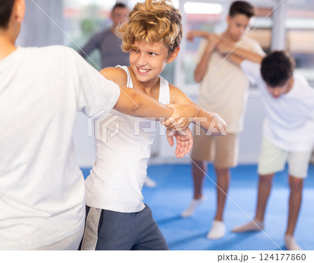 Diligent preteen student practicing self-defense techniques in pairs 124177860