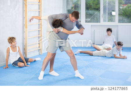 Instructor demonstrating self-defence techniques in sparring with student 124177865