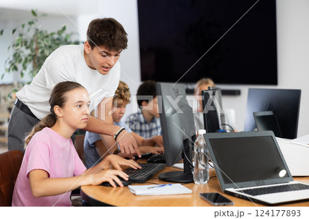Guy teacher teaches girl student how to use computer 124177893