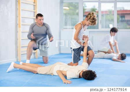 Teenager applying armlock technique to face-down opponent at self-defense classes 124177914