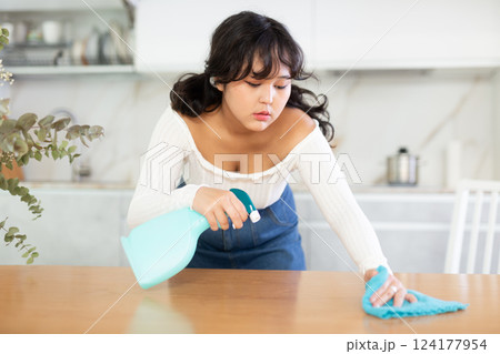 Girl washing of kitchen table during cleanup in apartment 124177954