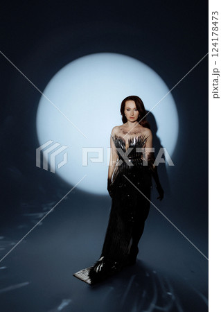 Glamorous Woman in a Metallic Dress Posing Under Dramatic Spotlight Glamorous Woman in a Metallic Dress Posing Under Dramatic Spotlight 124178473