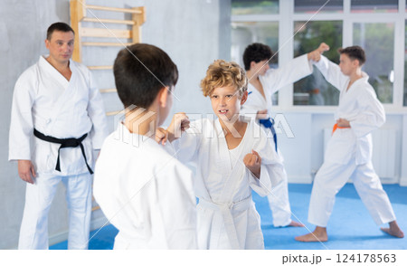 Karate kids in kimono sparring together during their group karate training in modern sports gym 124178563