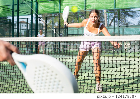 Young woman padel tennis player trains on the outdoor court Young woman padel tennis player trains on the outdoor court 124178587