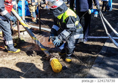 出初式で消火活動の実演を披露し消防ホースを片付ける消防隊員 124178730