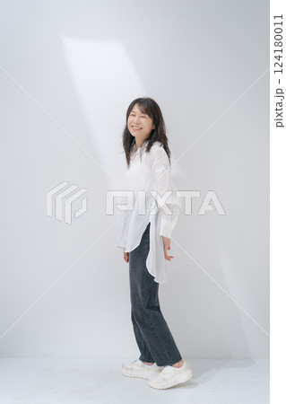 白い壁の前に立っているミドル女性 124180011