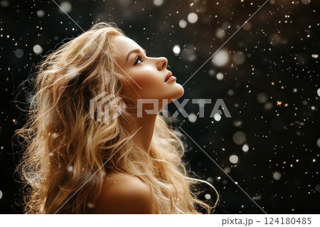 Beautiful blonde woman with long, curly hair in a nightdress standing under a snowfall. Beautiful blonde woman with long, curly hair in a nightdress standing under a snowfall. 124180485