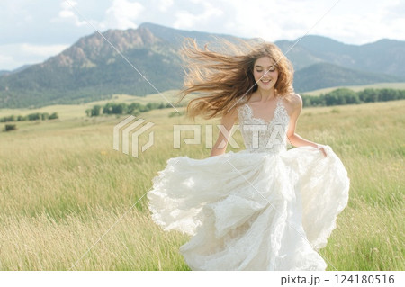 Portrait of a beautiful young woman in a white dress running through a grassy field. Portrait of a beautiful young woman in a white dress running through a grassy field. 124180516
