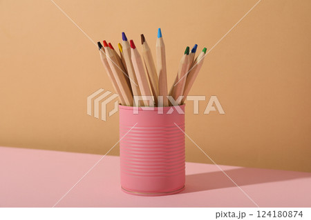 Colored pencils in pink tin can on beige background 124180874