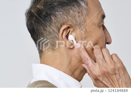 ワイヤレスイヤホンを使う私服姿のシニア男性 ワイヤレスイヤホンを使う私服姿のシニア男性 124184889