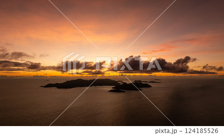 Golden sunset over distant islands with a cloudy sky and calm ocean waters. Seychelles. 124185526