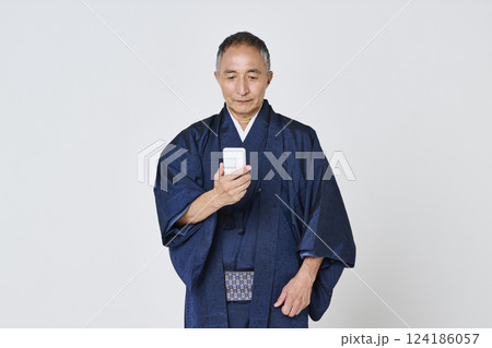 スマートフォンを使う紺色の着物を着たシニア男性 スマートフォンを使う紺色の着物を着たシニア男性 124186057