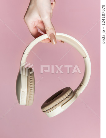 Woman holding wireless headphones on pink background Woman holding wireless headphones on pink background 124187679