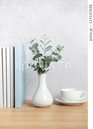 Eucalyptus branches, books, and coffee cup creating a cozy atmosphere on wooden desk Eucalyptus branches, books, and coffee cup creating a cozy atmosphere on wooden desk 124187686