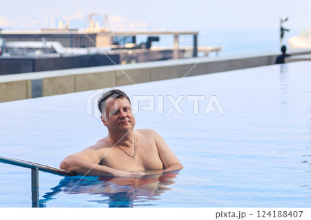 Serious man relaxing in outdoor pool in evening 124188407