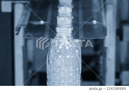 The empty drinking water bottles on the conveyor belt for filling process in the light blue scene. The empty drinking water bottles on the conveyor belt for filling process in the light blue scene. 124190989