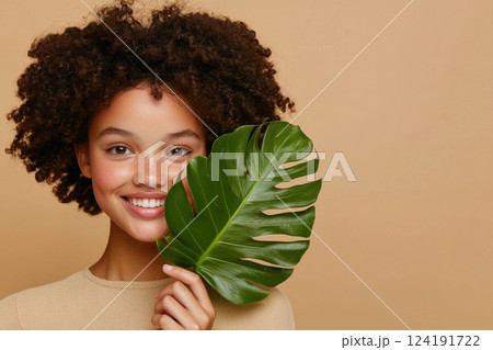Radiant Woman Touching Green Leaf on Her Face 124191722
