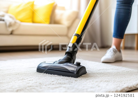 Woman Cleaning Living Room with Vacuum Cleaner 124192581