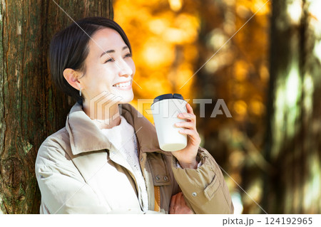 紅葉を楽しみながらホットドリンクを飲む女性 ライフスタイルイメージ 紅葉を楽しみながらホットドリンクを飲む女性 ライフスタイルイメージ 124192965