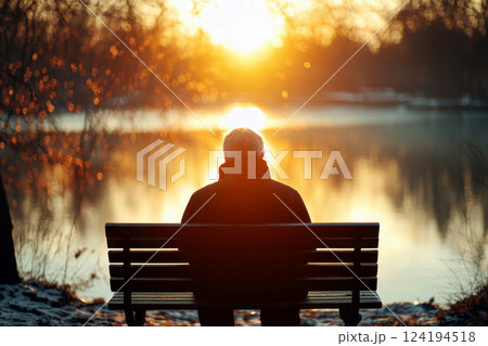 Lonely Old Man in Park Sitting on a bench by a sunlight flare lake. Lonely Old Man in Park Sitting on a bench by a sunlight flare lake. 124194518