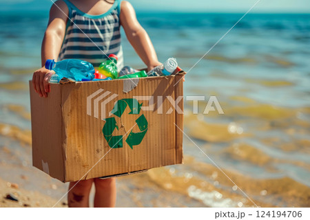 hands holding a recycling box filled with various recyclable items on beach ..Environment Day concept. Generative AI 124194706
