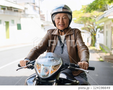 住宅街でバイクにまたがる元気なシニア女性 124196649