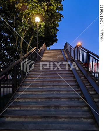 The staircase leading up, deserted at dusk surrounded by a tree, is beautiful and atmospheric 124196659