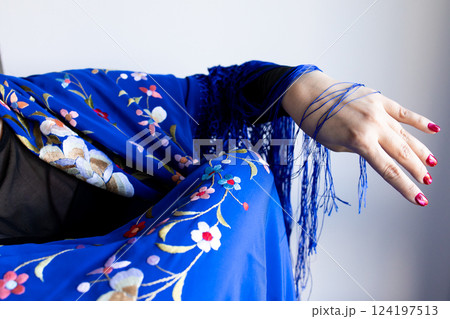 Elegant female arm in floral blue shawl with fringe details 124197513