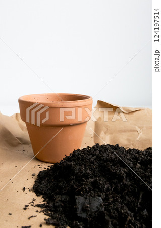 Empty terracotta pot with soil on craft paper against white background Empty terracotta pot with soil on craft paper against white background 124197514