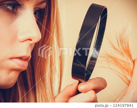 Sad woman looking at damaged hair ends. Sad woman looking at damaged hair ends. 124197841