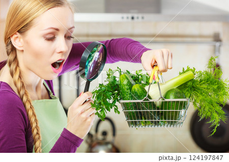 Woman looking through magnifier at vegetables basket 124197847