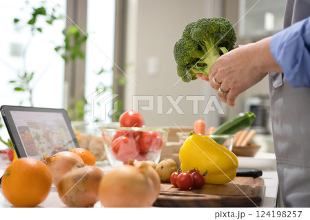 タブレットを見ながら料理をするミドル女性 タブレットを見ながら料理をするミドル女性 124198257
