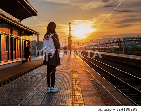 夕暮れの無人駅で列車を待つ学生 124198299