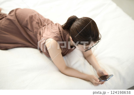 ベッドでくつろいでスマホを見る若い女性 124198638